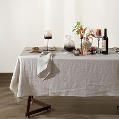 a table with wine bottles, candles and other items on it in front of a white wall