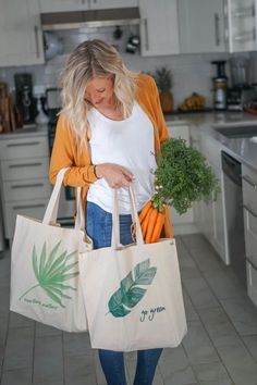 a woman is holding two bags with carrots on them and a plant in it