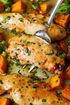 a close up of chicken and vegetables in a pan with a spoon on top of it