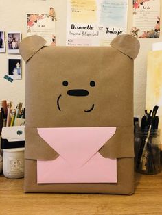 a paper bag with a bear face on it and a pink envelope in the front