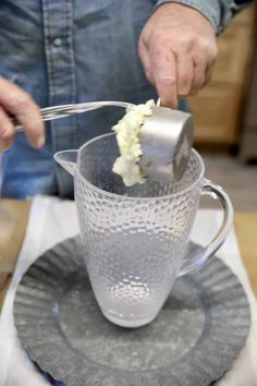 a person pouring cream into a glass cup