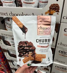 someone is holding up a bag of churros in front of some chocolate bars