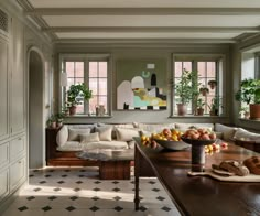 a living room filled with lots of furniture next to two windows and potted plants