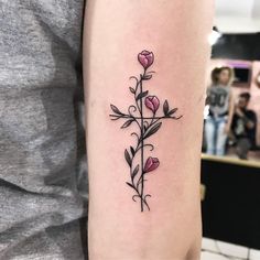 a cross tattoo with flowers on the arm