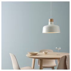 a dining room table with two chairs and a light hanging over it, in front of a blue wall