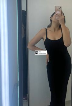 a woman in a black dress taking a selfie