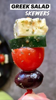 a hand holding a piece of food that is stacked on top of each other with the words greek salad skewers above it