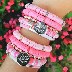 three pink and white bracelets with monogrammed charms on each one, along with the word'm '