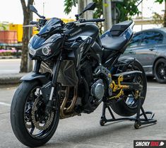 the motorcycle is parked on the side of the road next to some cars and trees