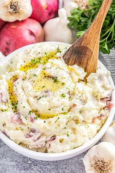 a bowl filled with mashed potatoes and parsley next to garlic, onions, and other vegetables