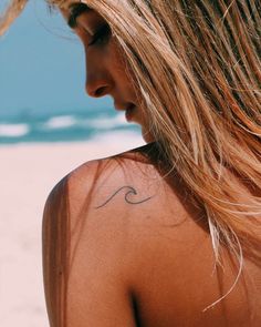 the back of a woman's shoulder with a wave tattoo on it