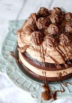 a cake with chocolate frosting and nuts on top sitting on a blue platter