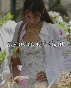 a woman wearing a white dress and pearls in her hair with the words, my aura is bright