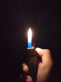 a person holding a lighter in their hand with the light on it's side