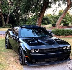 a black sports car parked on the side of a road in front of some trees