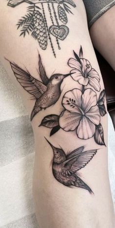 a woman's thigh with hummingbirds and flowers on her leg, tattoo style