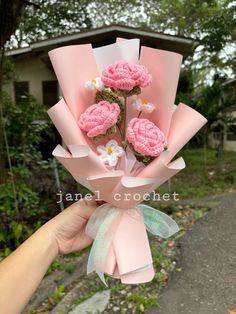 a hand holding a bouquet of pink flowers