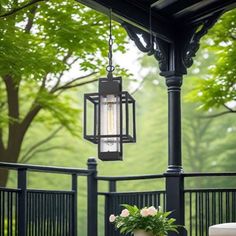 a lamp hanging from the side of a porch next to a table with flowers on it