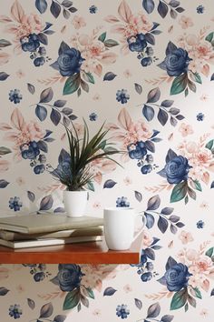 two mugs are sitting on a shelf in front of a floral wallpaper