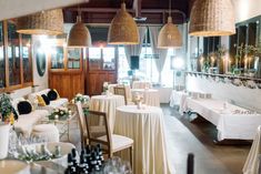 a restaurant with tables and chairs covered in white tablecloths, hanging lights above them