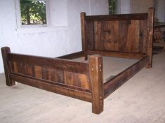 a bed frame made out of wood in a room with white walls and flooring