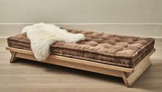 a dog bed that is made out of wood and has sheep fur on top of it