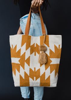 A girl can never have too many totes - especially when they're this cute! Our newest Aztec inspired tote is a must have for running errands or your next weekend getaway. Cream and camel Aztec inspired tote Camel pom tassel detail Leather suede straps Measures 16" x 6" x 16" Designed in the U.S.A. Produced in India.  100% Cotton Lining: 100% Polyester Blouses Vintage, Flannel Sweatshirt, Knit Jewelry, Easy Street, Women Accessories Bags, Boho Bag, Bag Travel, Large Bag, Weekend Getaway