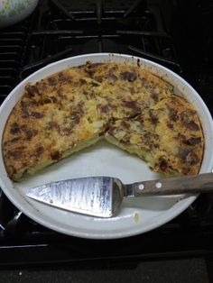 a pizza sitting on top of a white plate next to a knife and spatula