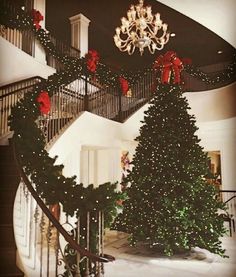 a christmas tree sitting on top of a stair case next to a chandelier