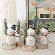 four snowmen with hats and scarves on their heads are standing in front of a painting