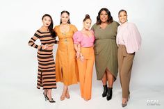 four women posing for the camera in front of a white background wearing different colored outfits