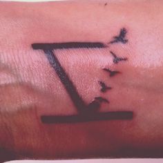 a person with a tattoo on their arm that has the letter z in it and birds flying around