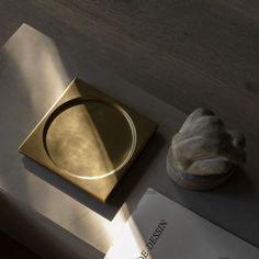 a gold plate sitting on top of a table next to a book and a stone