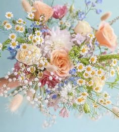 a bouquet of flowers is being held by someone's hand on a blue background