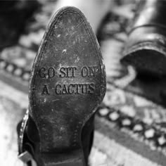 black and white photograph of someone's shoes with the words go sit on a cactus