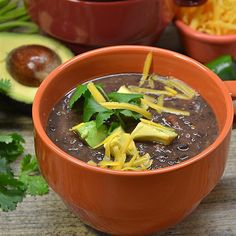 a bowl of black bean soup with cheese and avocado