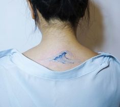 a woman's back neck with a wave tattoo on it