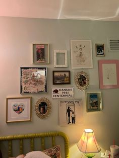 a bedroom with pictures on the wall and a lamp