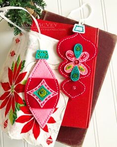 two red and green ornaments sitting on top of a white cloth bag next to a christmas tree