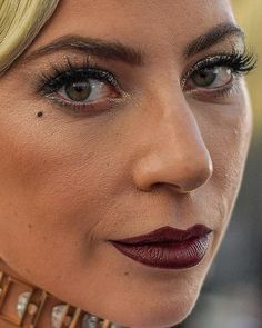 close up of lady with red lipstick and gold choker on her neck looking at the camera