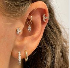 a close up of a person wearing ear rings and earrings with leaves on the side