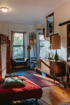 a living room filled with furniture and windows next to a wooden floor covered in rugs