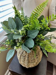 a basket filled with green plants sitting on top of a table next to a couch