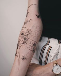 a woman's arm with flowers and bees on it