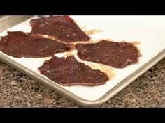 three pieces of raw meat on a white plate next to a knife and some brown stuff