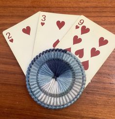 three playing cards with blue and white designs on them sitting on top of a wooden table