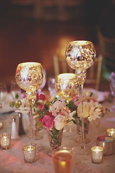 the table is set with candles, flowers and wine glasses for an elegant wedding reception