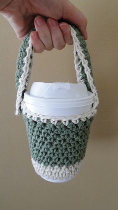 a hand holding a coffee cup in a crocheted bag