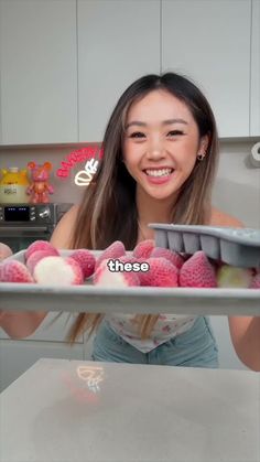 a woman holding a tray full of pink and white balls