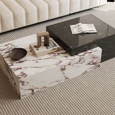 a marble coffee table sitting on top of a floor next to a couch and book